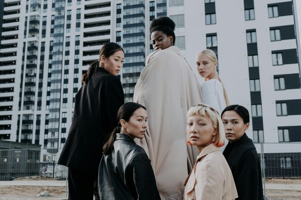 Group of diverse women modeling fashion in a modern urban setting with high-rise buildings.