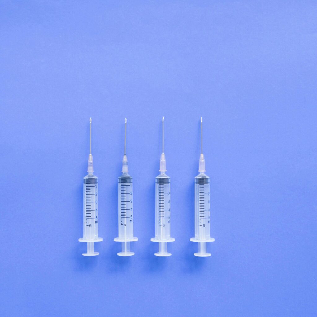 Four syringes aligned on a blue background, symbolizing medical and healthcare concepts.