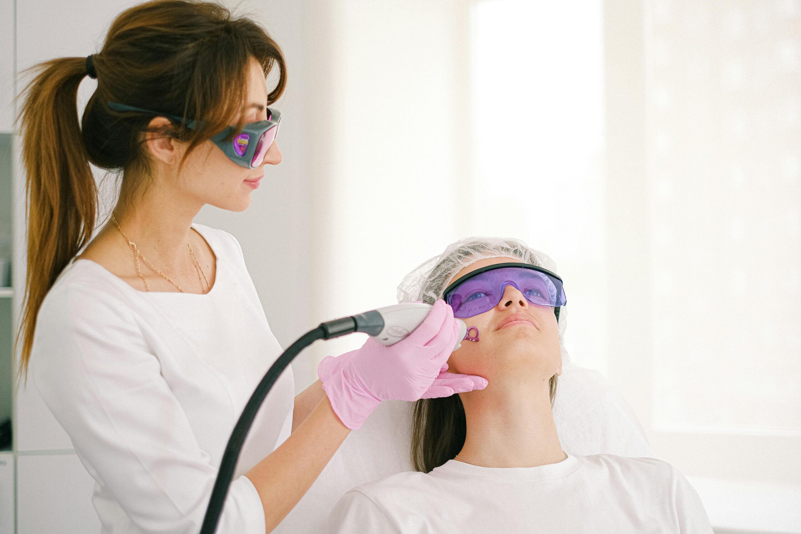 home - beauty directory - A cosmetologist performing laser treatment on a woman in a clinic setting.