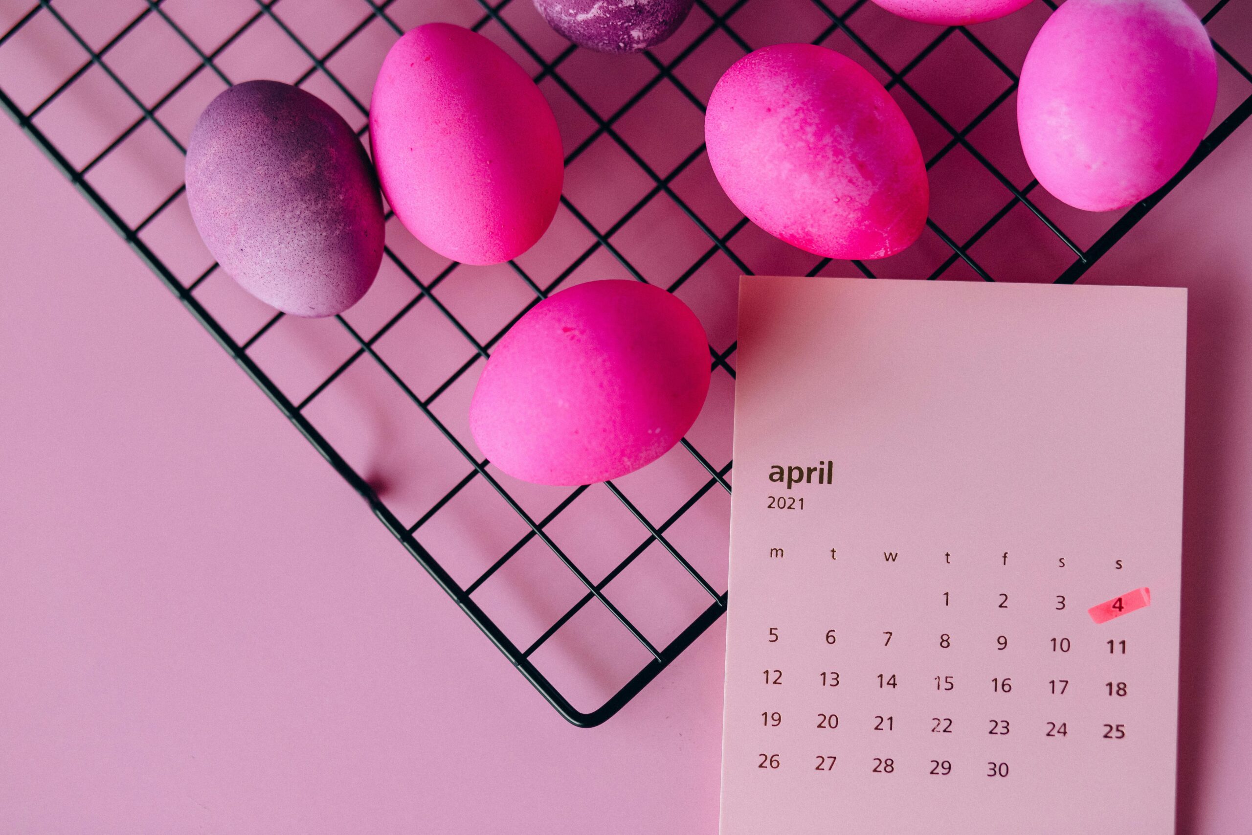 Colorful Easter eggs on a rack and an April 2021 calendar, symbolizing spring celebration.