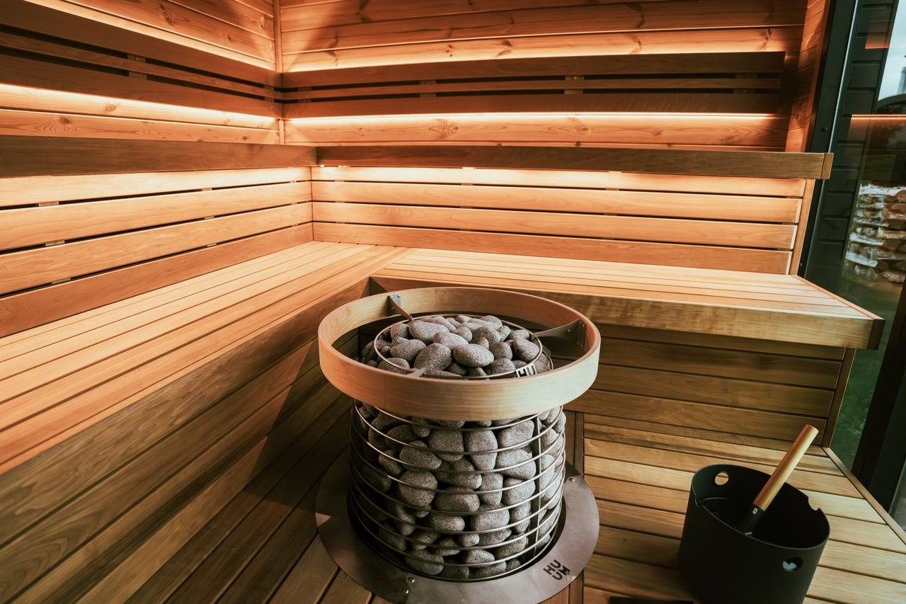 A beautifully designed wooden sauna interior featuring a modern heater with stones, creating a relaxing atmosphere.