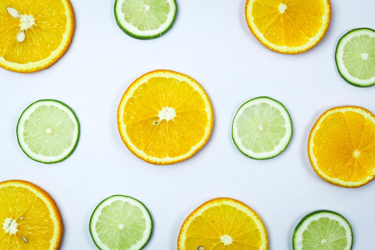 Vibrant orange and lime slices arranged on a white surface, showcasing freshness and color.