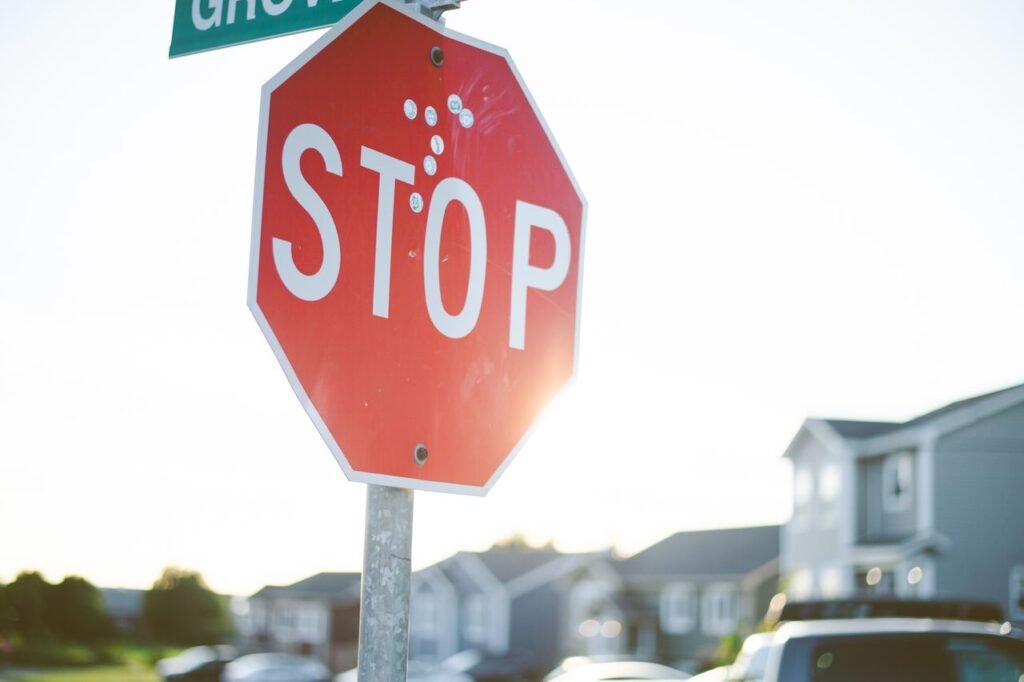 Close-up shot of a stop sign with sunny, blurred suburban background.